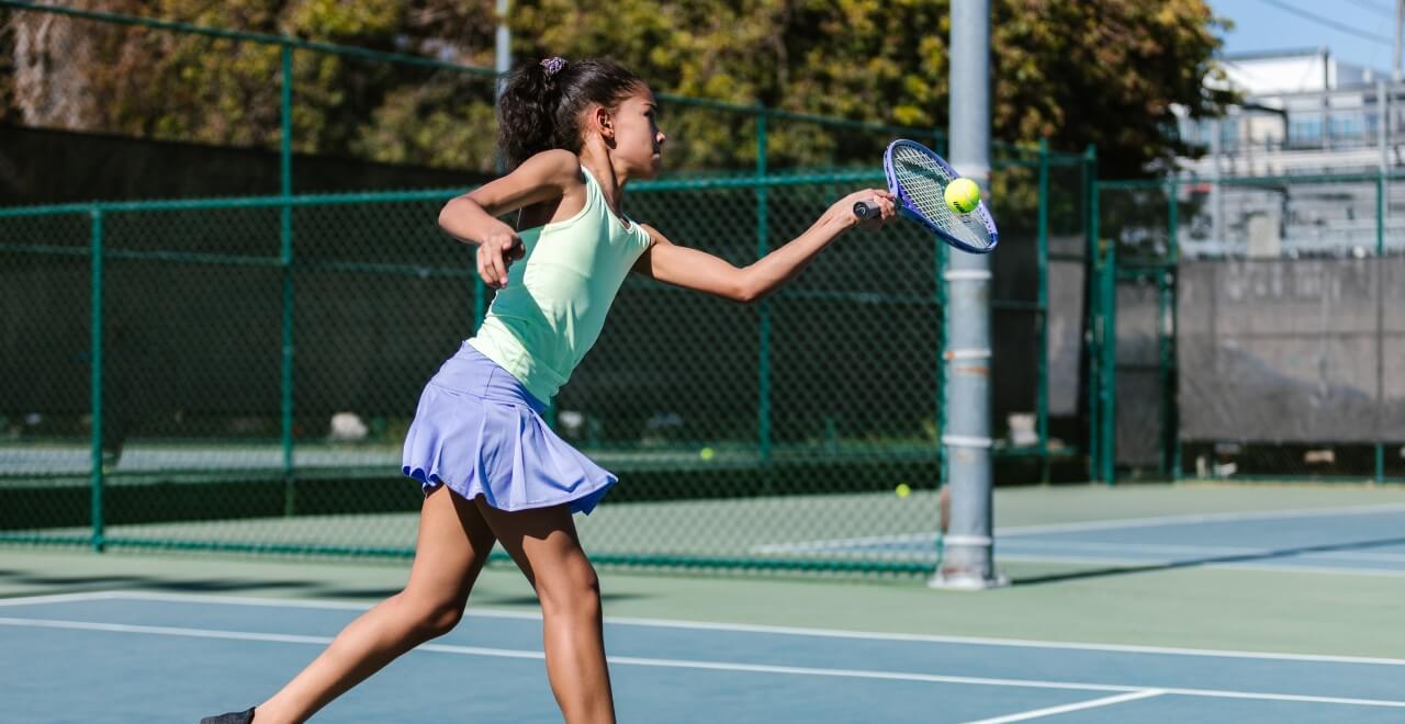 teenage girl hitting tennis ball