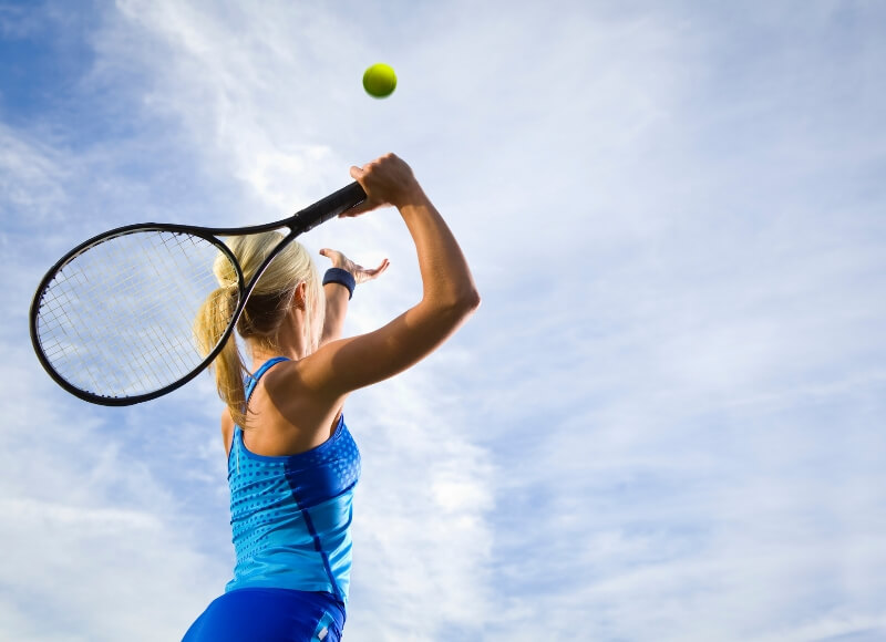 young girl serving tennis